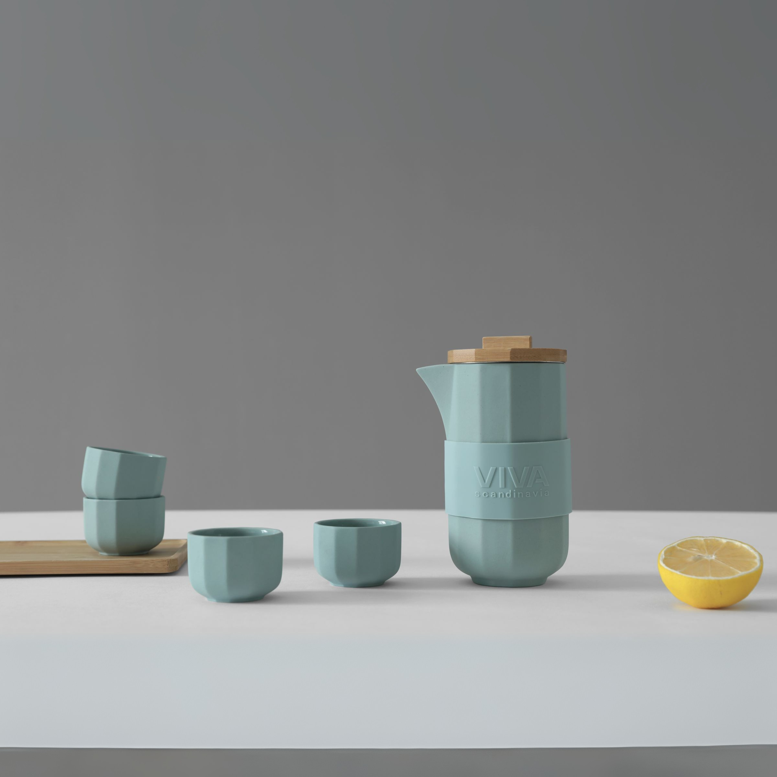 Groene Alexander theeset met kopjes en theepot op tafel, vergezeld van een halve citroen voor frisse sfeer.