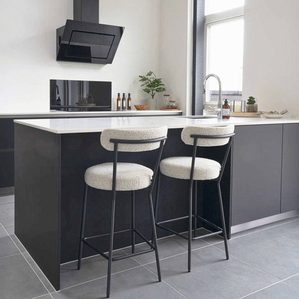 Twee Badalona barkrukken met witte bouclé bekleding en zwart metalen frame aan een modern keukeneiland, stijlvolle inrichting van House Nordic.