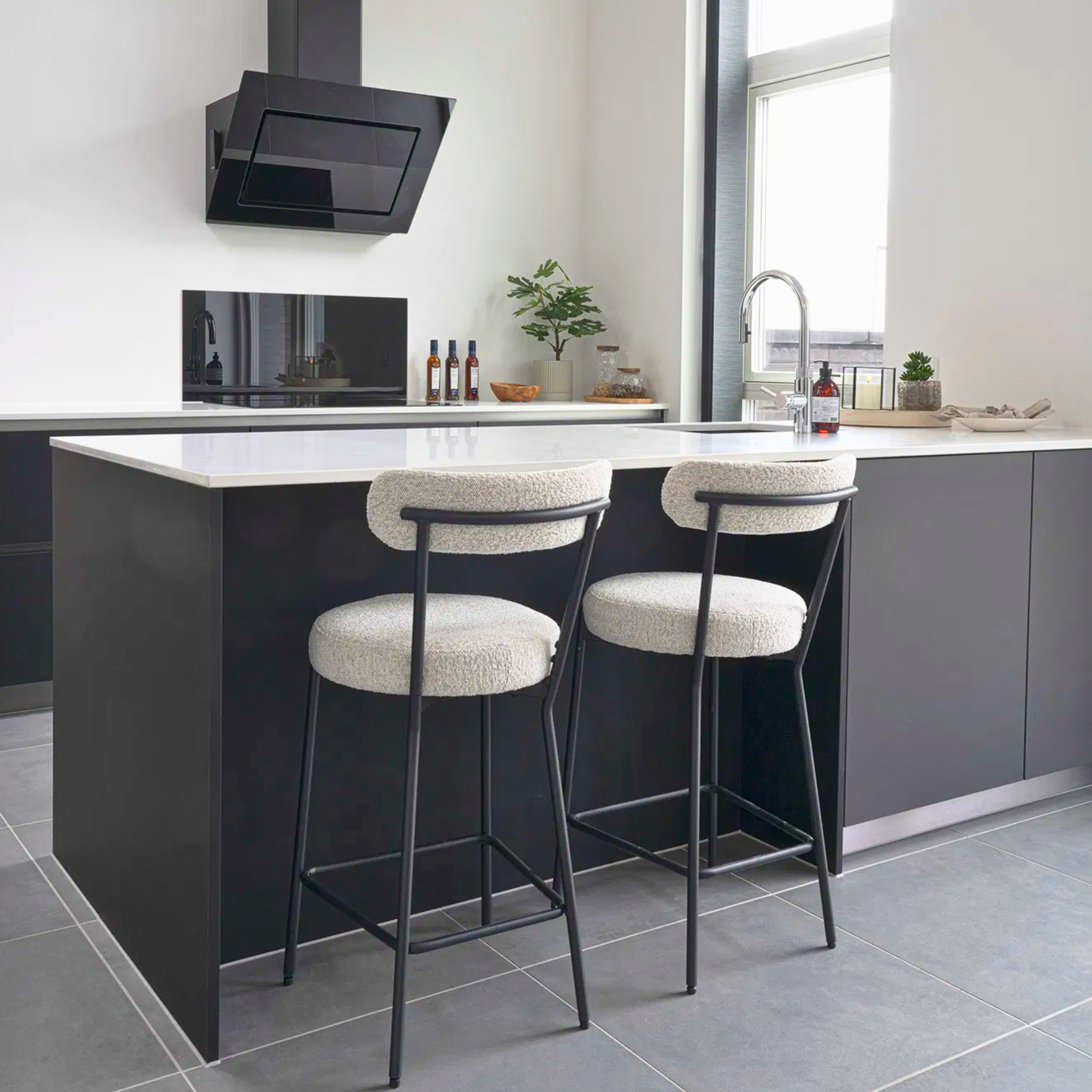 Twee Badalona barkrukken met witte bouclé bekleding en zwart metalen frame aan een modern keukeneiland, stijlvolle inrichting van House Nordic.