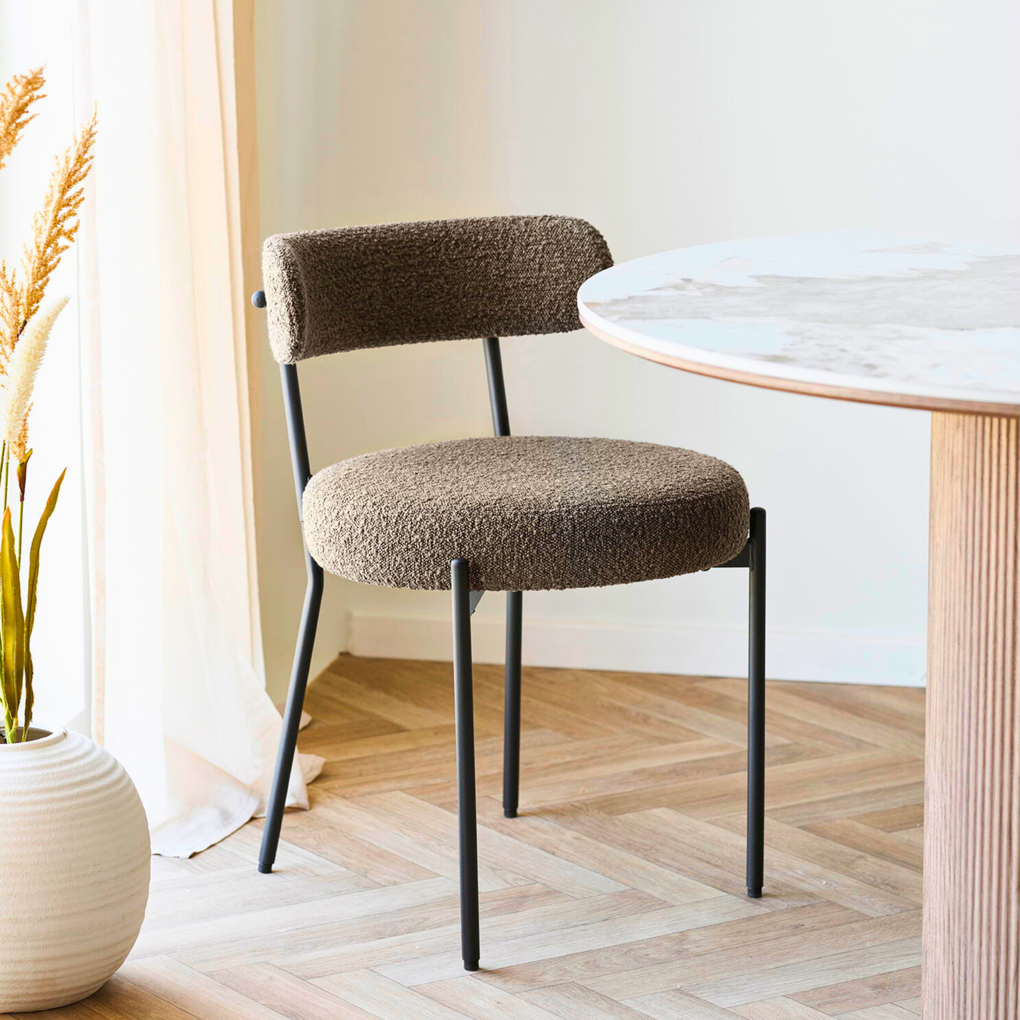 Set van Badalona eetkamerstoelen met bruine bouclé bekleding en zwarte metalen poten rond een moderne eettafel in een Scandinavisch interieur van House Nordic.