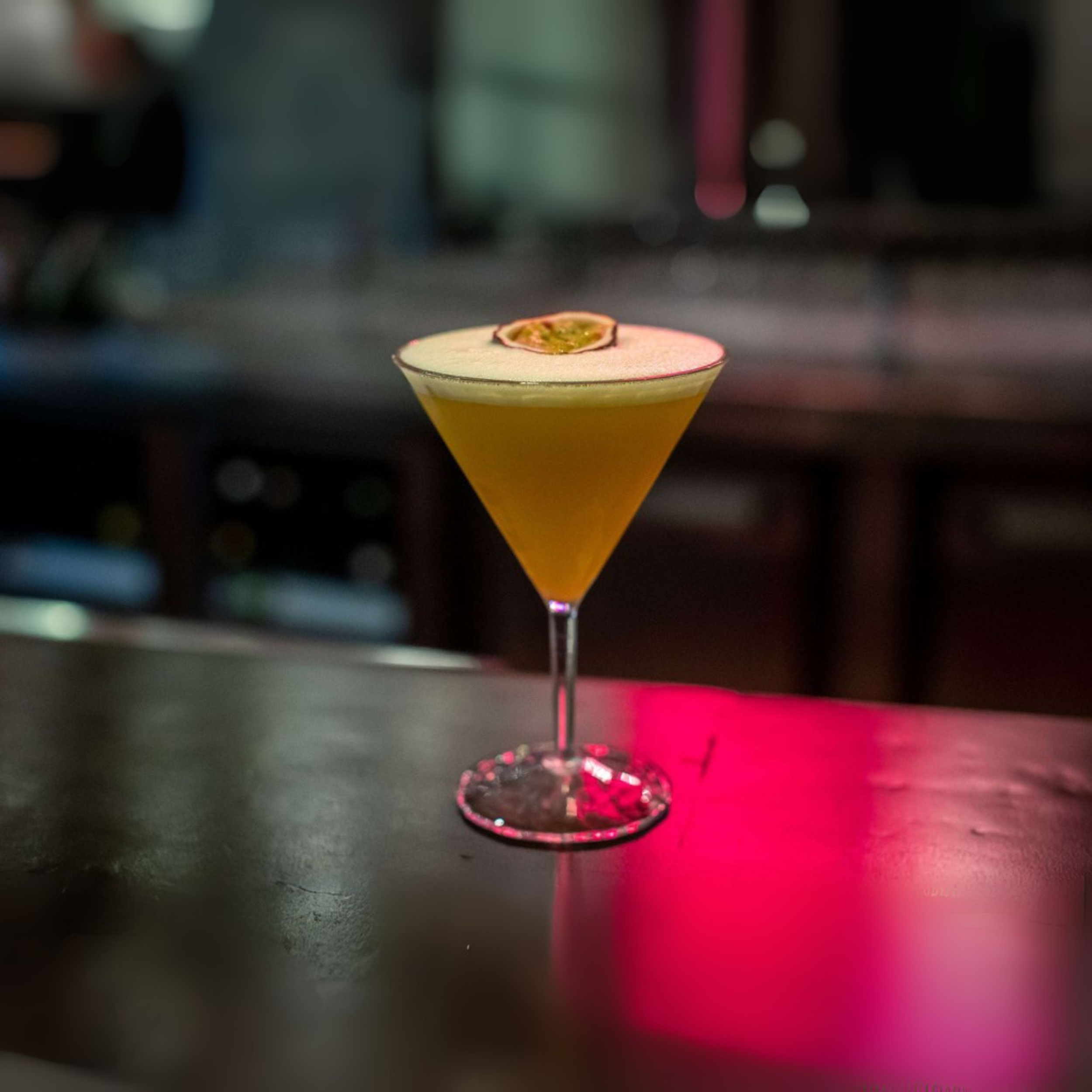 Koziol Superglas Club No. 12 cocktailglas van 250 ml gevuld met oranje cocktail en passievrucht, perfect voor bar of thuisgebruik.