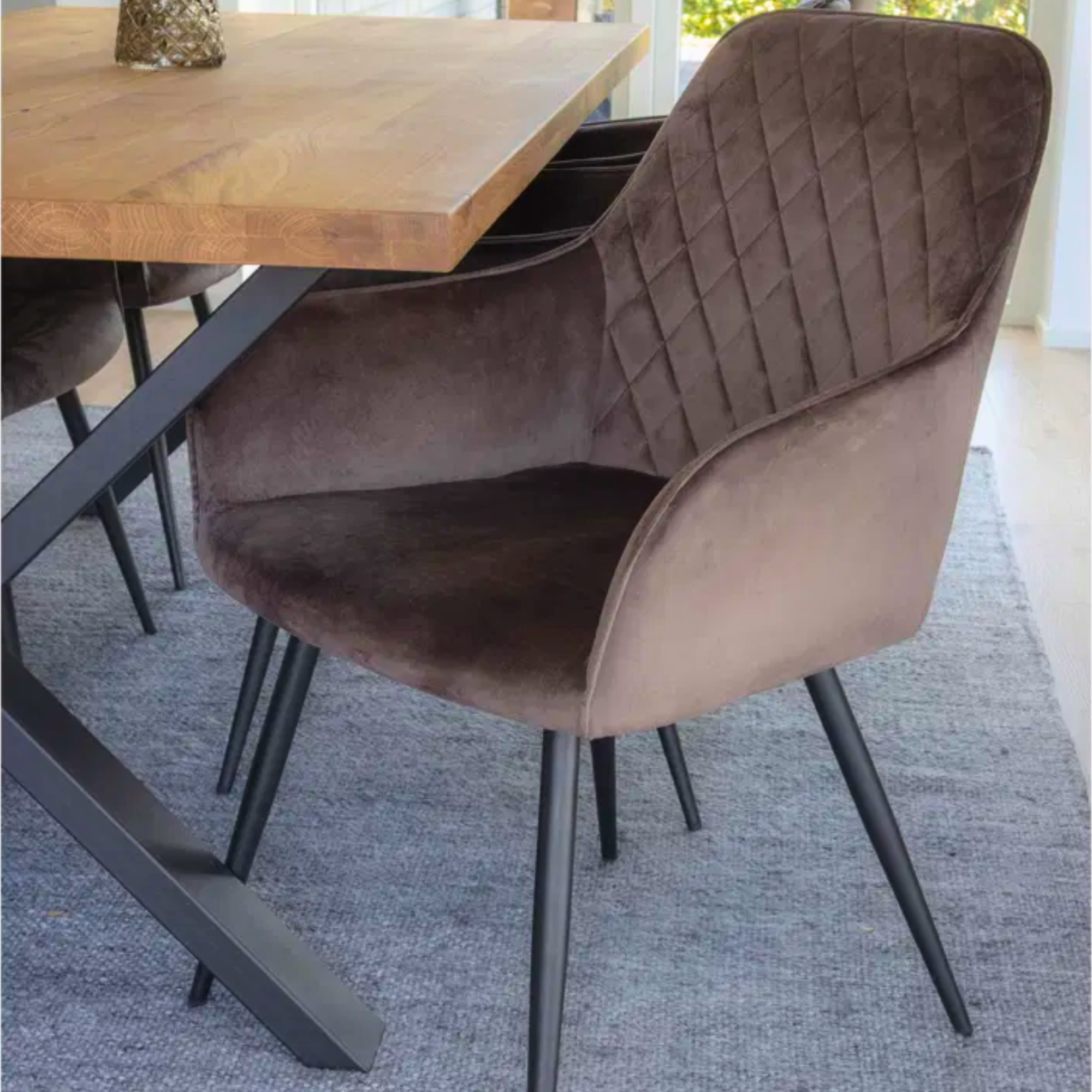 Voorzijde van Harbo eetkamerstoelen in bruin velvet rond een houten eettafel – moderne en stijlvolle eetkamerinrichting van House Nordic.