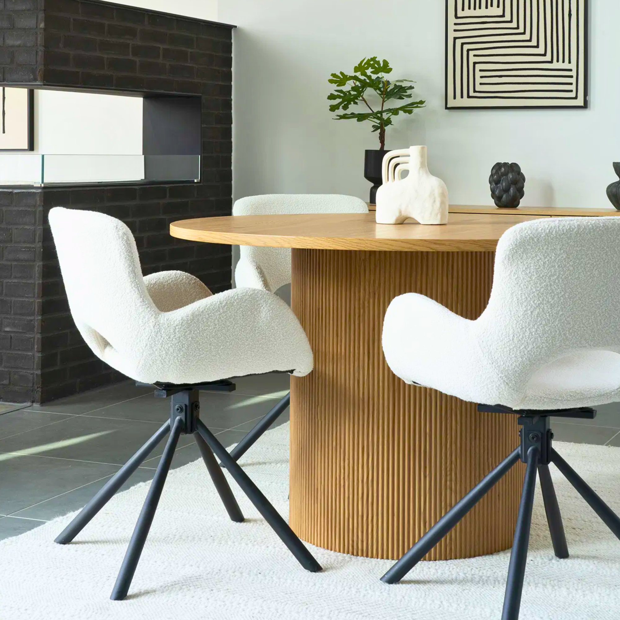 Set van Amorim eetkamerstoelen in off-white bouclé stof met zwarte metalen draaivoet, rond houten eettafel in een modern Scandinavisch interieur van House Nordic.