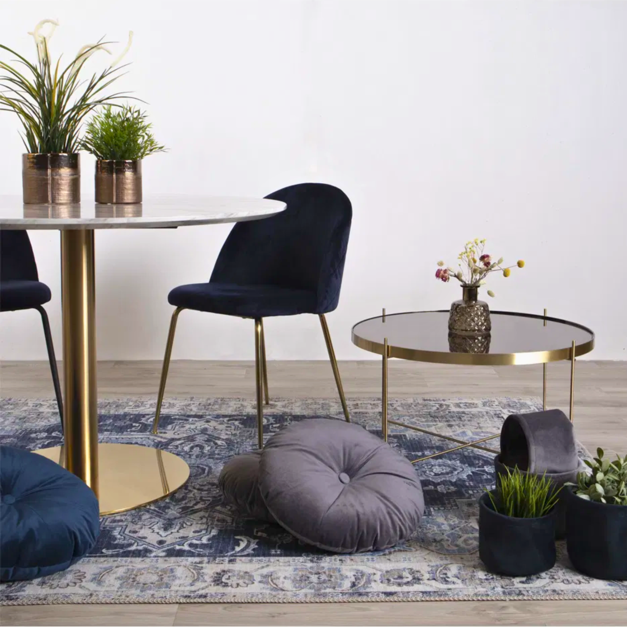 Donkerblauwe velvet Geneve eetkamerstoelen van House Nordic met gouden poten, geplaatst aan een marmeren eettafel met bijzettafel en decoratie in een Scandinavisch interieur – productfoto van Lunero.