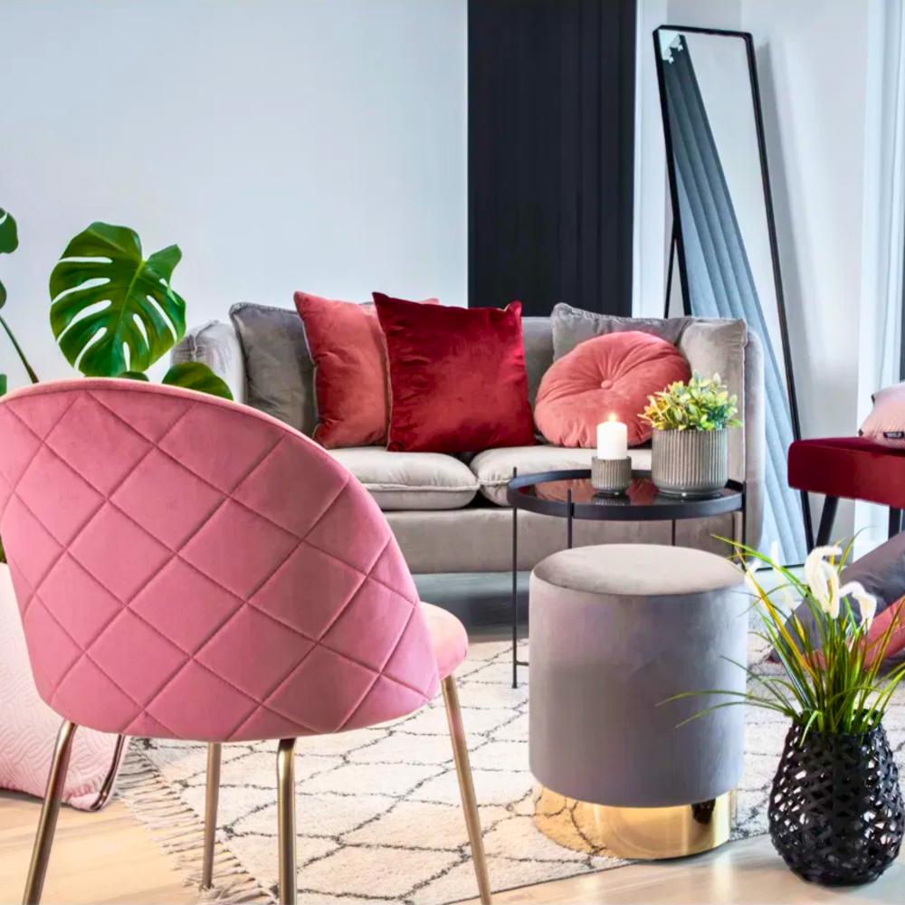 Roze velvet House Nordic Geneve eetkamerstoel met gouden poten in modern Scandinavisch interieur met grijze sofa en rode accenten.