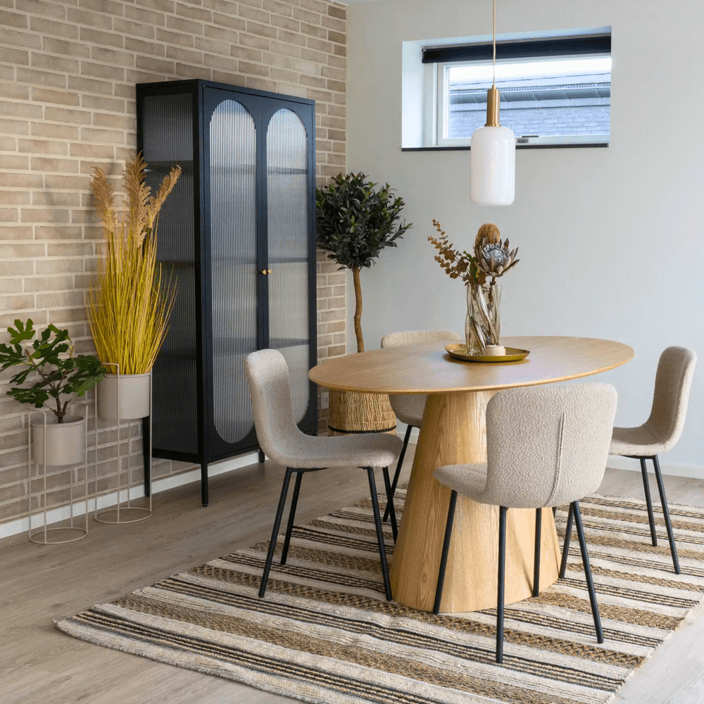 Sfeervolle eetkamer met Halden eetkamerstoelen van House Nordic in beige bouclé met zwarte poten, rondhouten tafel en Scandinavisch interieur.