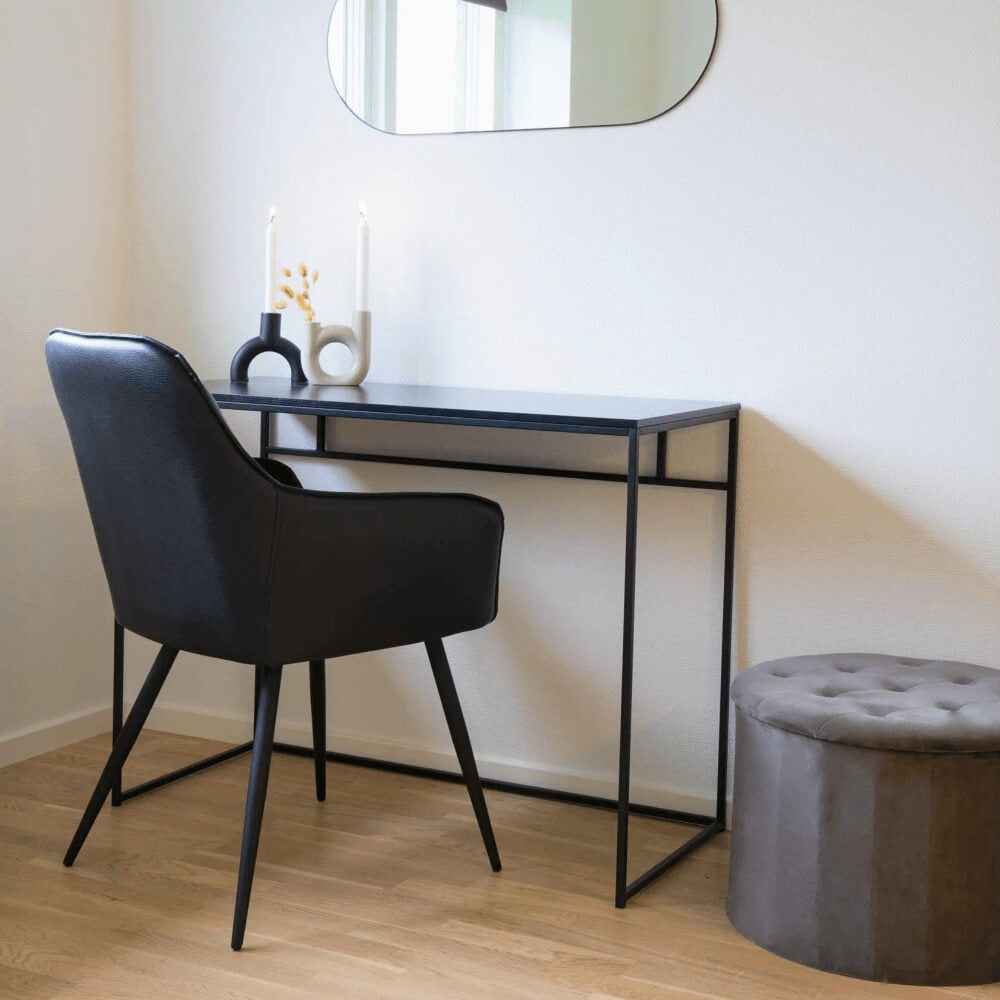 Zwarte House Nordic Harbo eetkamerstoel van PU-leer met armleuningen, gebruikt als bureaustoel in een modern Scandinavisch interieur.