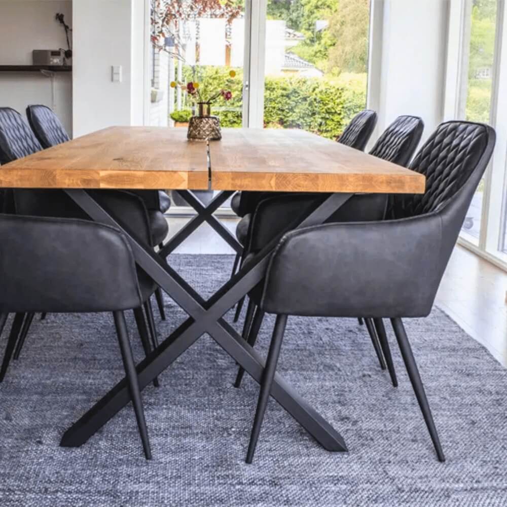 Zwarte House Nordic Harbo eetkamerstoelen van PU-leer rond een houten eettafel in een modern Scandinavisch interieur met veel natuurlijk licht.