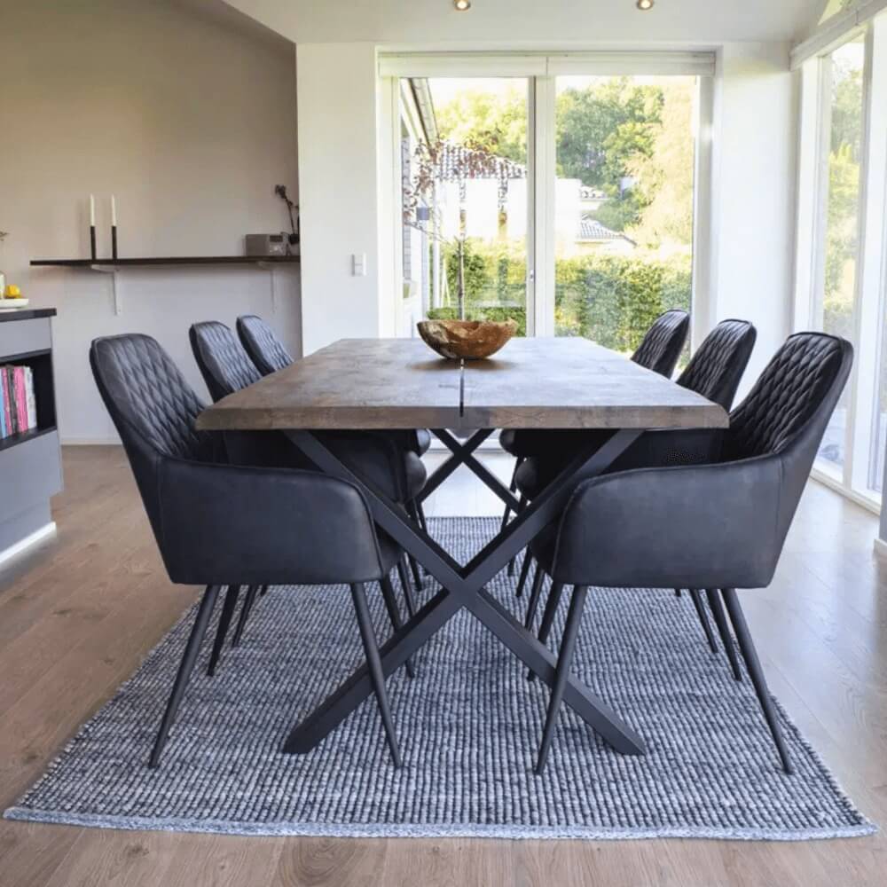 Set van zwarte House Nordic Harbo eetkamerstoelen rond houten eettafel – moderne eetkamer met PU-leren stoelen en zwarte metalen poten.