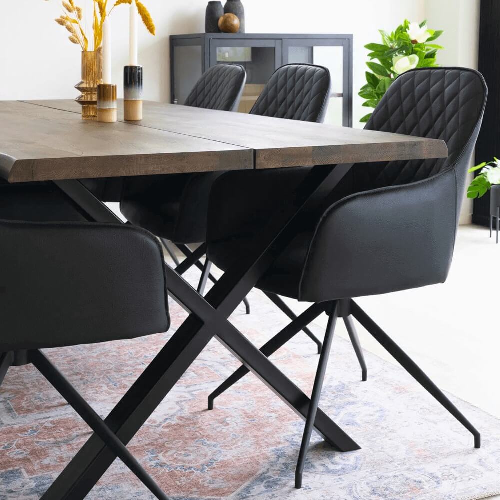 Close-up van zwarte House Nordic Harbo eetkamerstoelen in PU-leer rond een houten eettafel met Scandinavisch design.