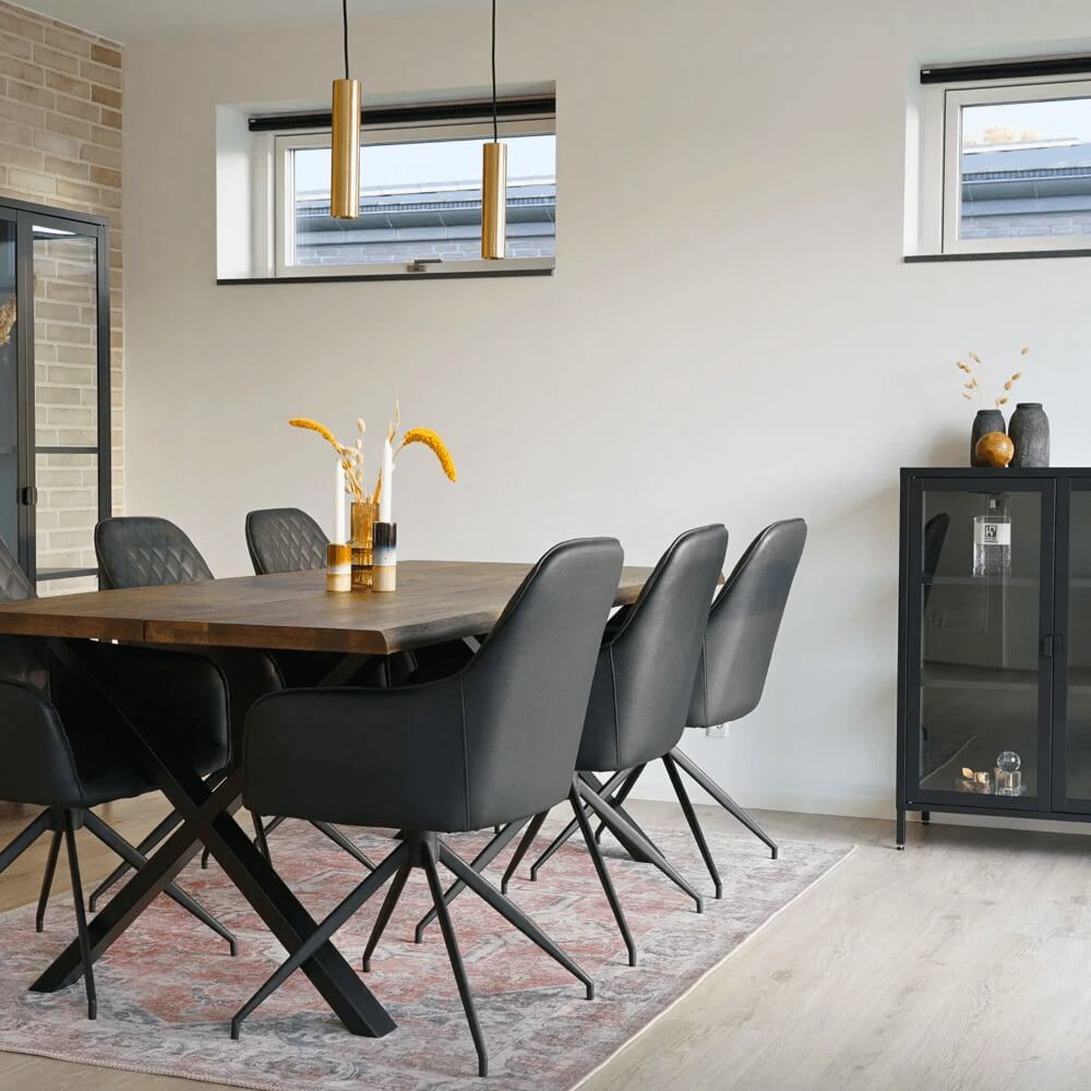 Moderne eetkamer met zwarte House Nordic Harbo eetkamerstoelen rond een houten tafel in Scandinavisch interieur met lichte muren en gouden accenten.