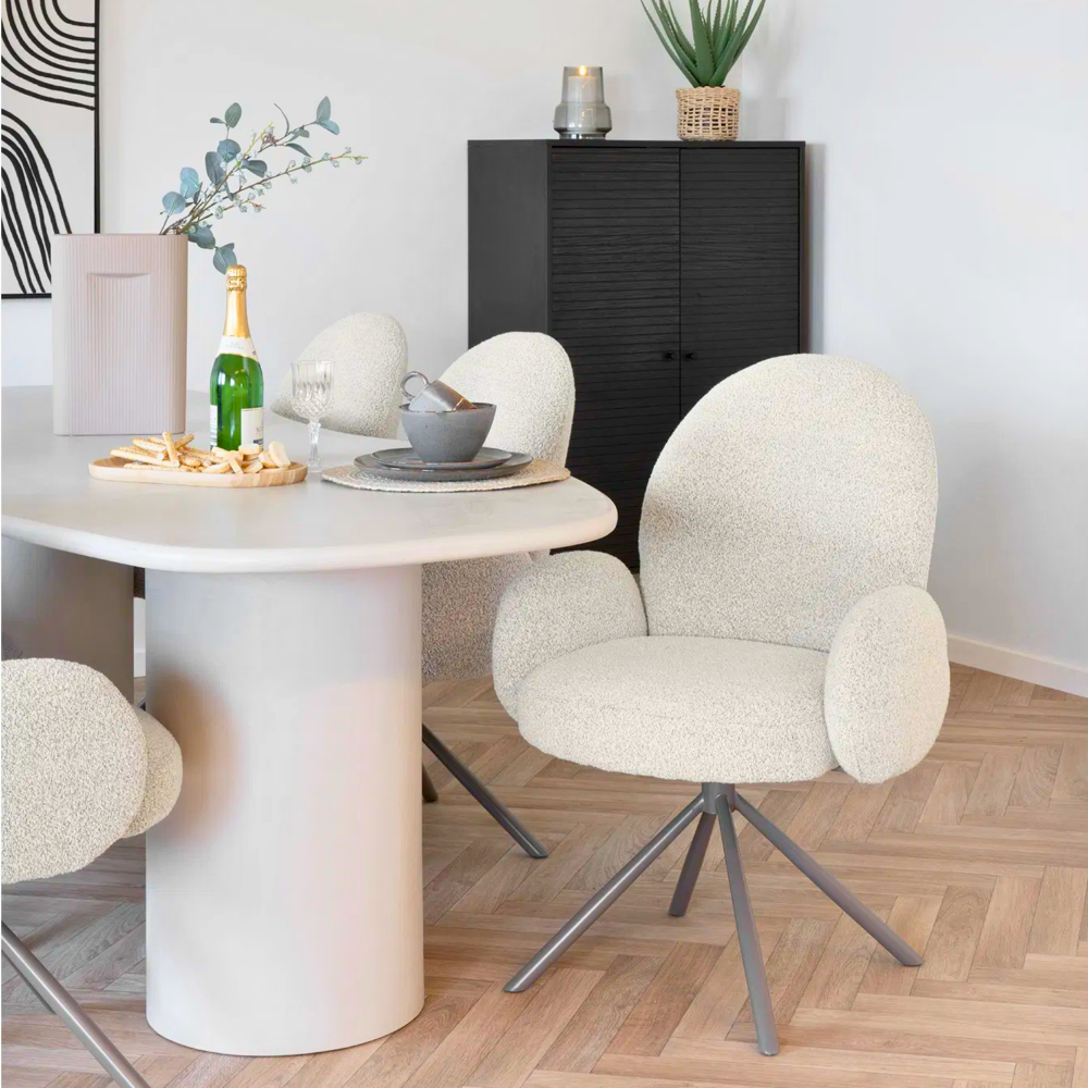 Twee House Nordic Lana eetkamerstoelen met armleuningen in zandkleurige bouclé stof aan een ronde eettafel in Scandinavisch interieur.