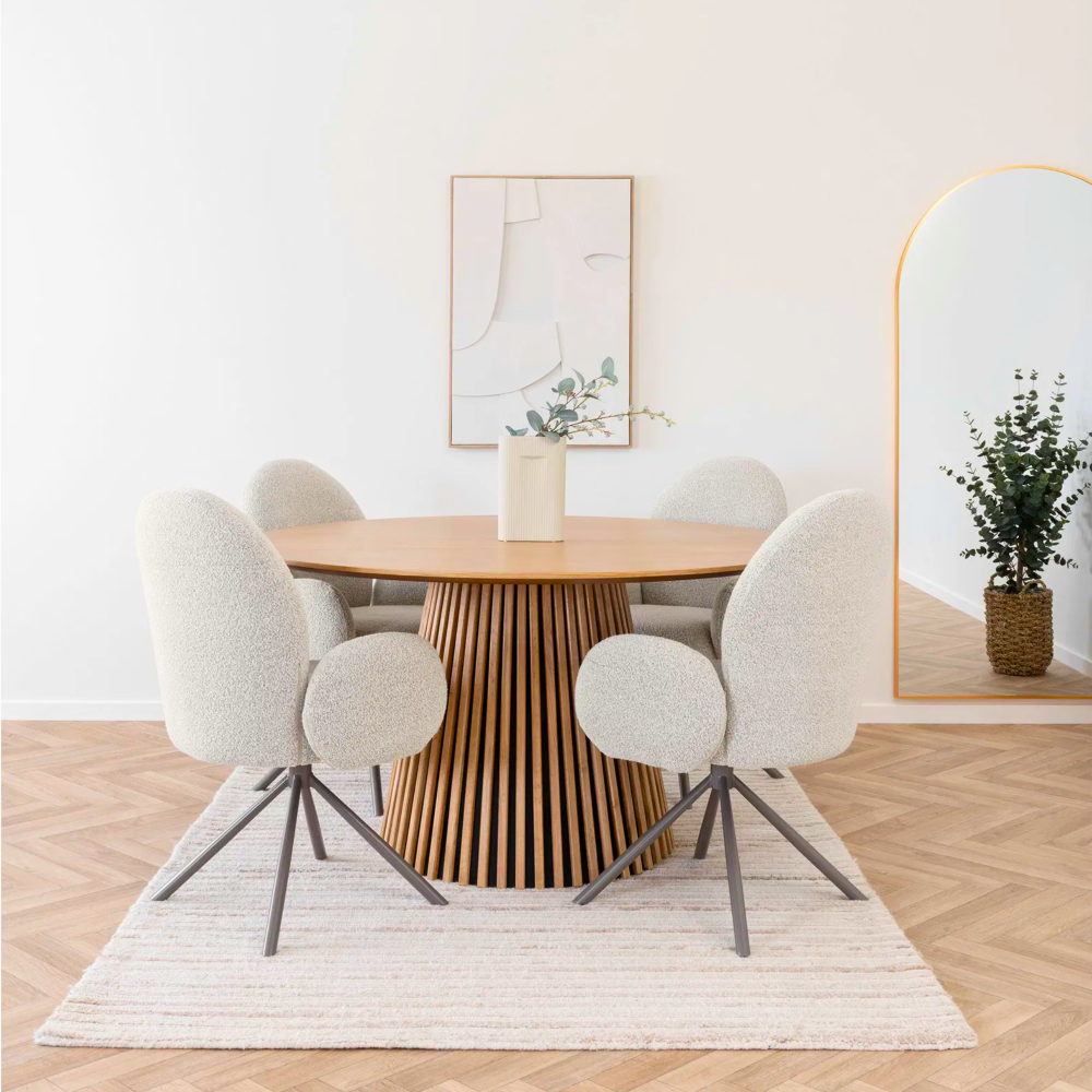 Vier House Nordic Lana eetkamerstoelen met armleuningen in zandkleurige bouclé stof rond een houten eettafel in Scandinavisch interieur met neutrale tinten.