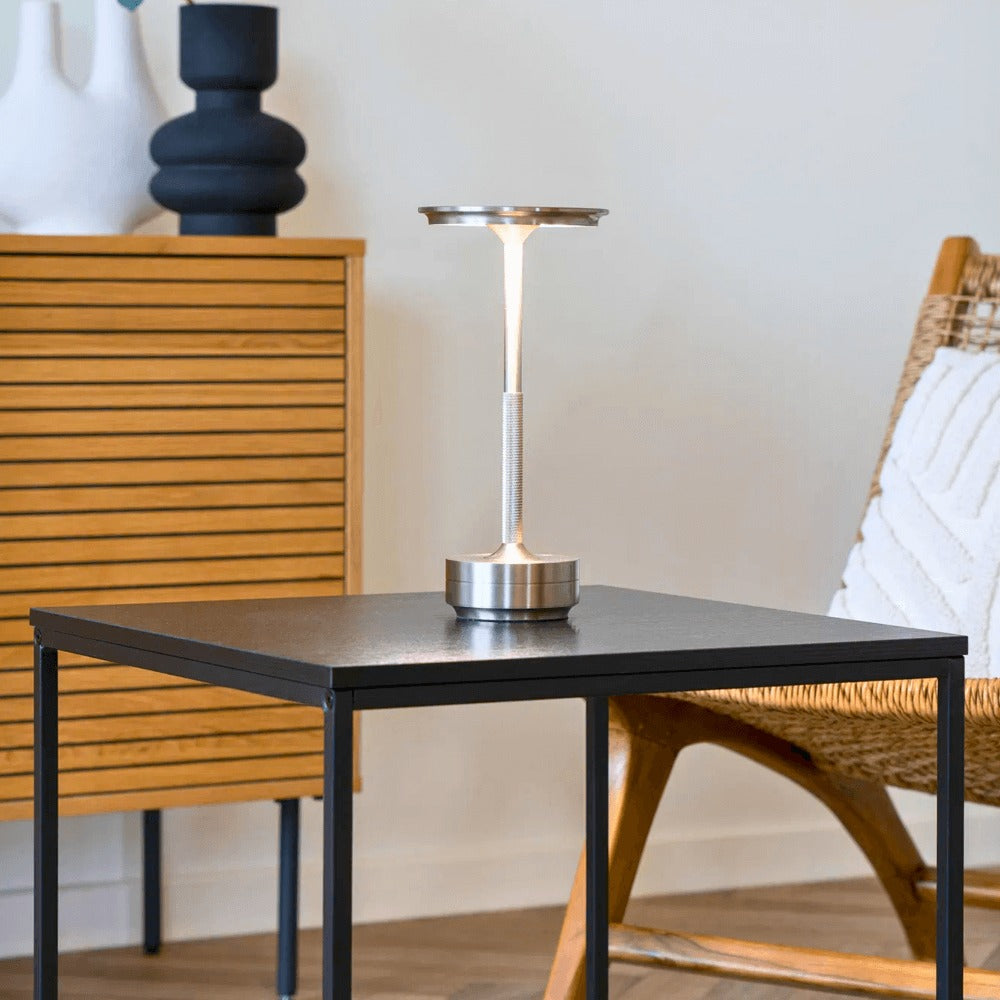 Zilveren Lyneham LED tafellamp van House Nordic op een zwarte bijzettafel in een modern Scandinavisch interieur.