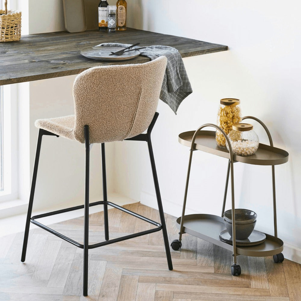 Beige bouclé barkruk van House Nordic met zwarte metalen poten aan houten keukentafel in modern Scandinavisch interieur.