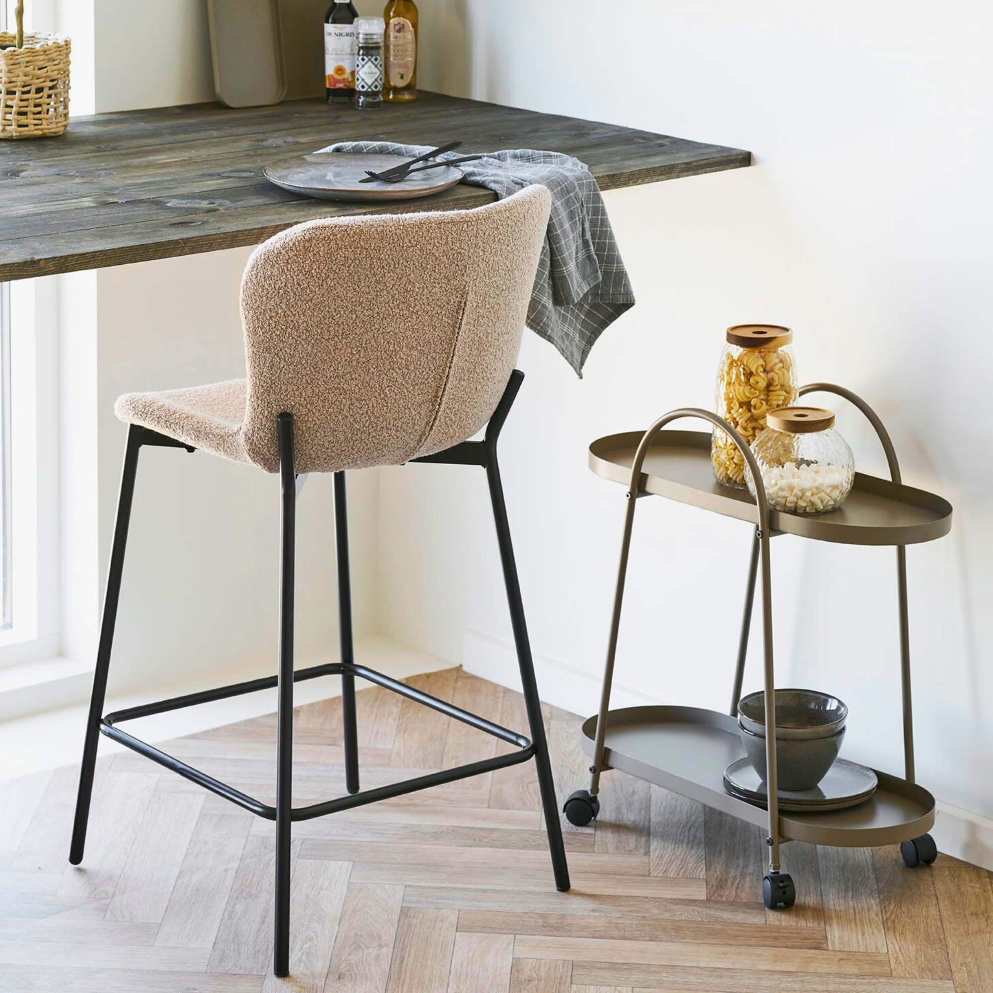 Beige bouclé barkruk van House Nordic met zwarte metalen poten aan houten keukentafel in modern Scandinavisch interieur.