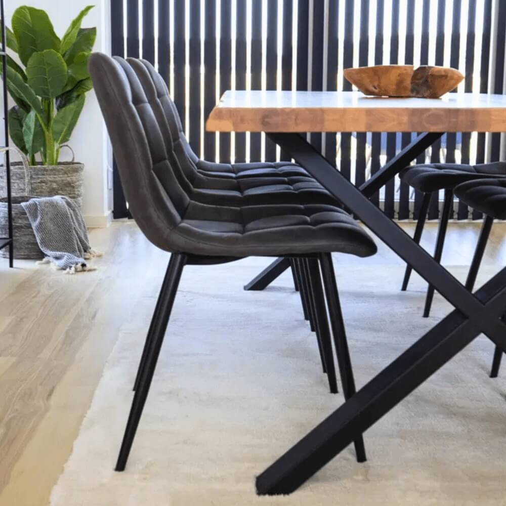 Close-up van House Nordic Middelfart eetkamerstoelen in donkergrijs microvezel met zwarte metalen poten aan houten eettafel in modern interieur.