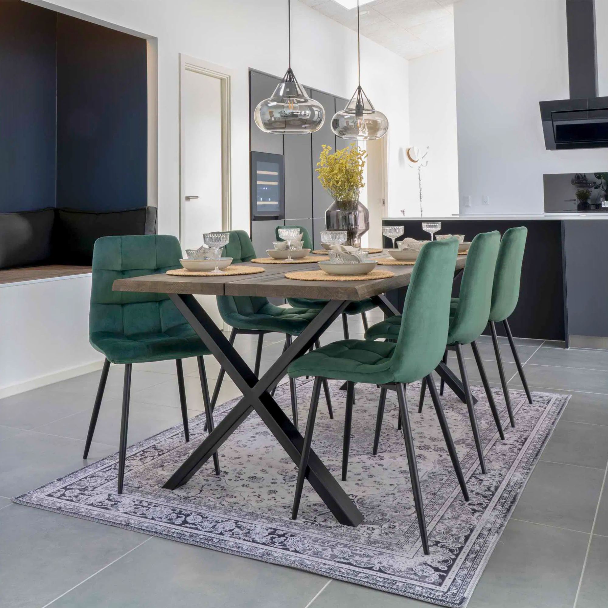 Moderne eetkamer met House Nordic Middelfart eetkamerstoelen in donkergroen velvet met zwarte poten aan houten eettafel met zwarte metalen poten.