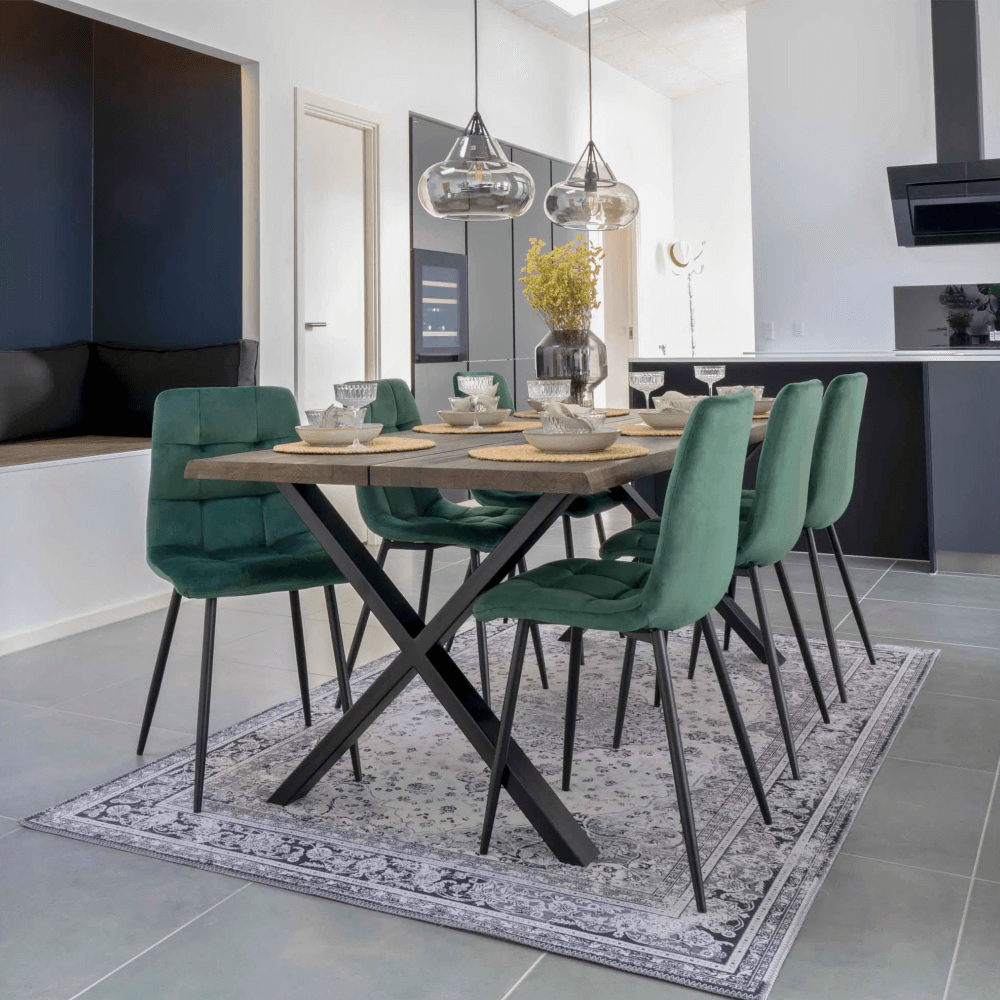 Moderne eetkamer met House Nordic Middelfart eetkamerstoelen in donkergroen velvet met zwarte poten aan houten eettafel met zwarte metalen poten.