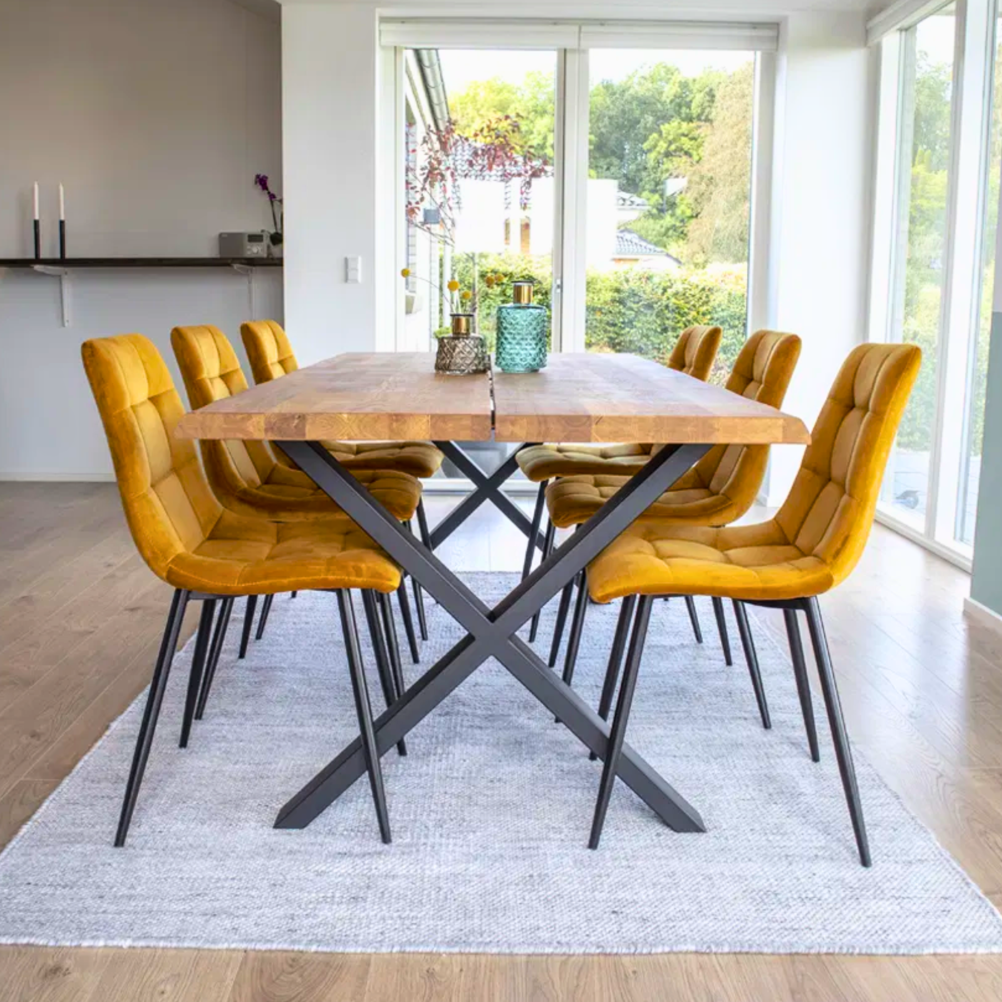 Scandinavisch interieur met House Nordic Middelfart eetkamerstoelen in geel velvet met zwarte poten rond houten eettafel in lichte eetkamer.