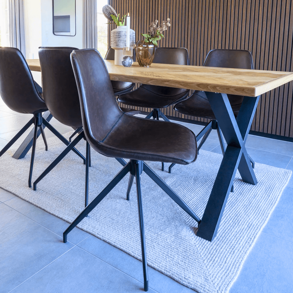 Donkerbruine Monaco eetkamerstoelen van House Nordic in PU-leer met zwarte metalen poten, geplaatst rond een houten eettafel in modern interieur.