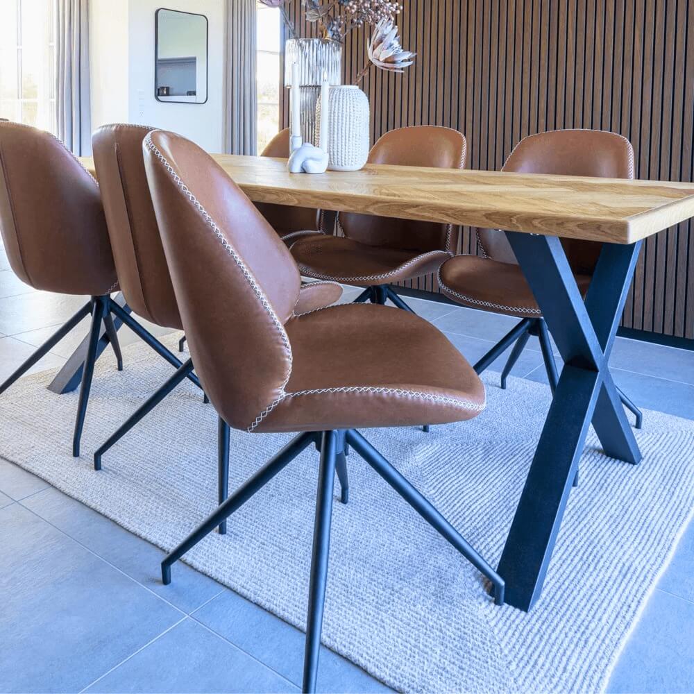 Monte Carlo eetkamerstoelen van House Nordic in bruin PU-leer rond een houten eettafel met zwarte metalen poten in modern interieur.