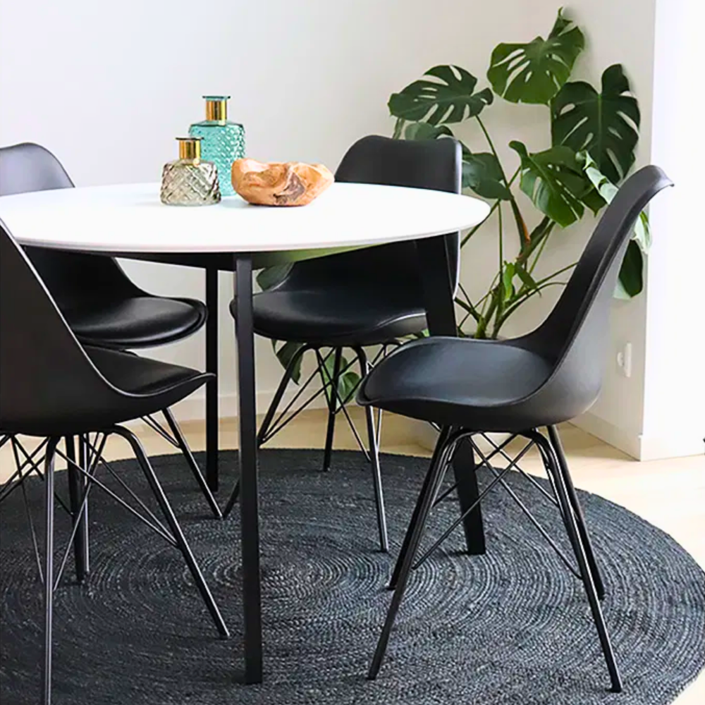 Sfeerbeeld van de House Nordic Oslo eetkamerstoel in zwart met zwarte poten, geplaatst rond een witte eettafel in een Scandinavisch interieur.