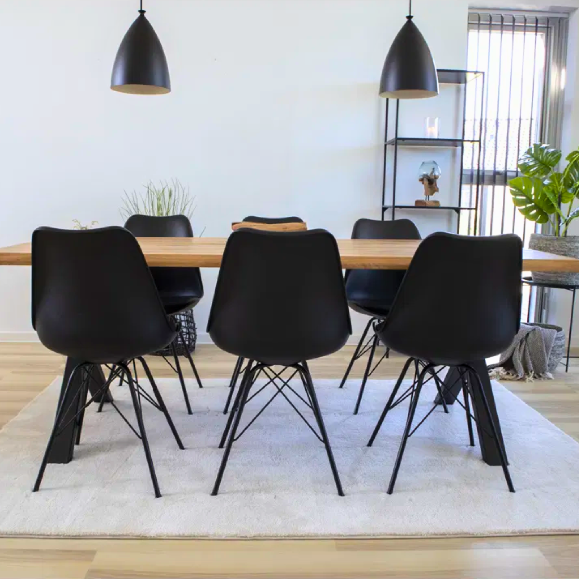 Zwarte House Nordic Oslo eetkamerstoelen rond een houten eettafel in een Scandinavisch interieur met minimalistische verlichting en plantenaccenten.