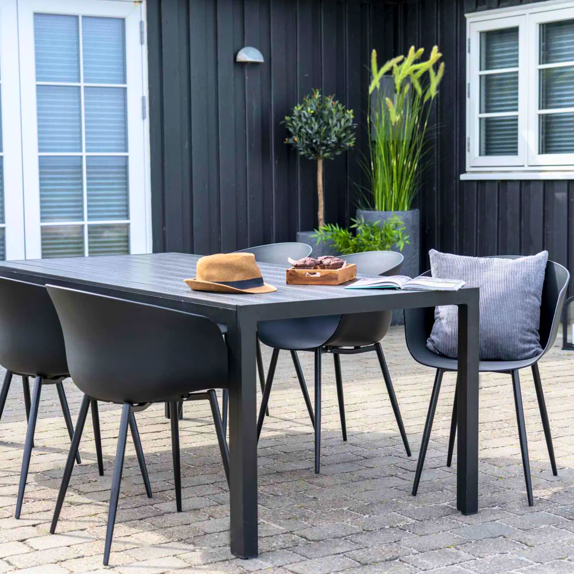 Set van zwarte House Nordic Roda eetkamerstoelen aan buitentafel op modern terras – Scandinavisch design met comfortabele uitstraling.