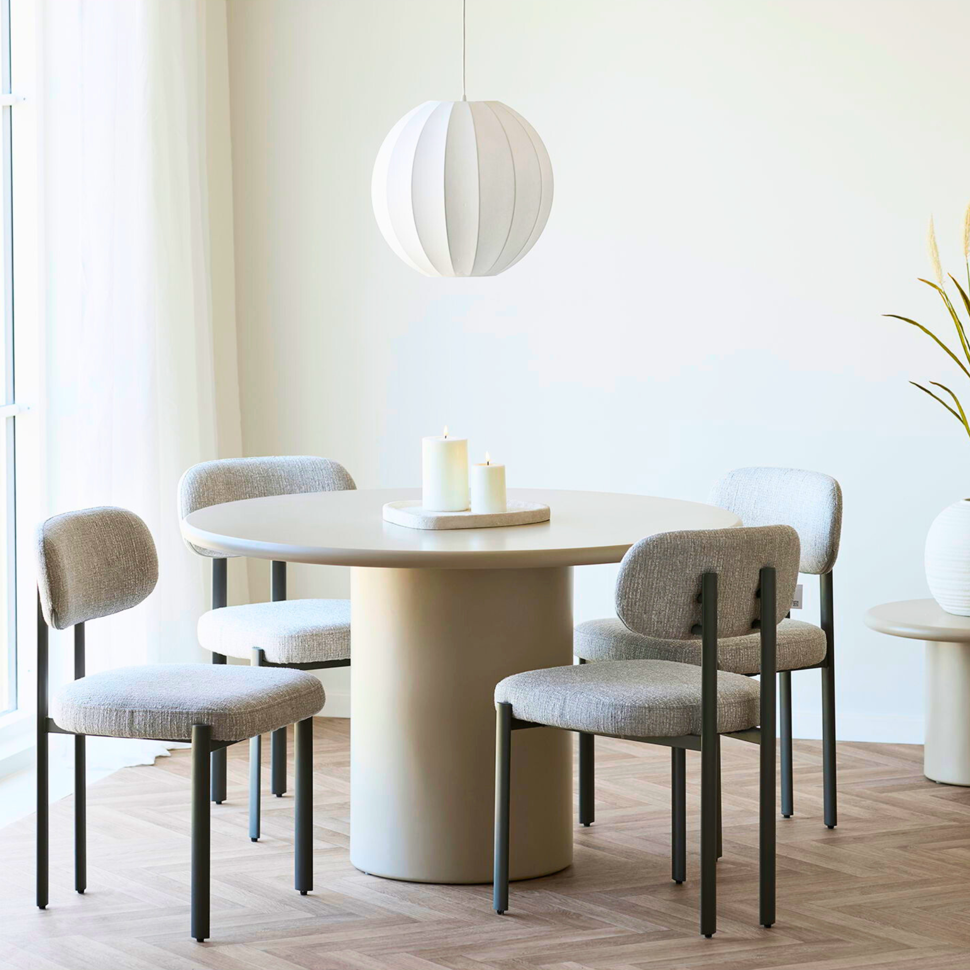 Lichtgrijze House Nordic Royan eetkamerstoelen met grijze poten rond beige eettafel in Scandinavisch interieur met houten vloer en witte lamp.