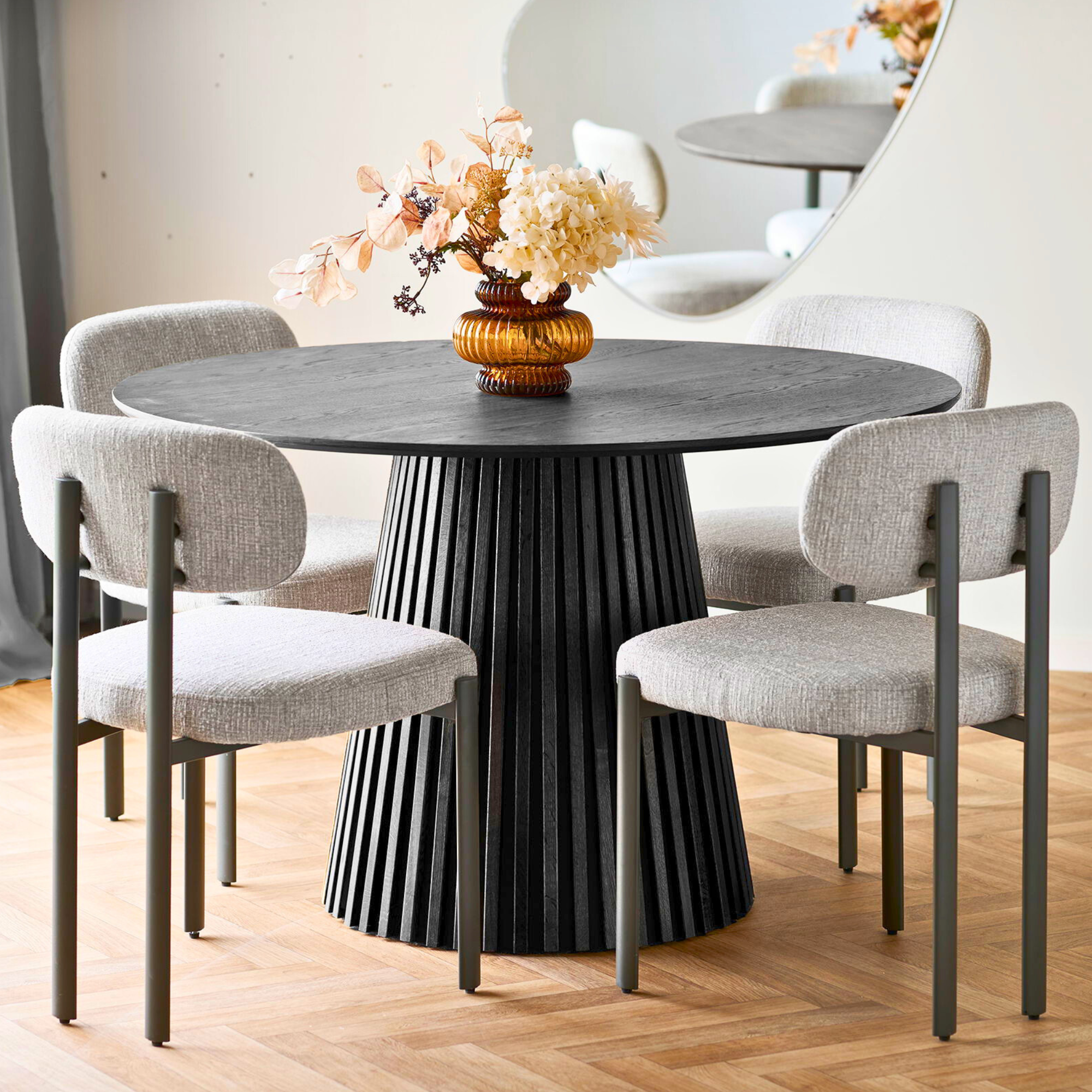 Vier House Nordic Royan eetkamerstoelen in lichtgrijs met grijze metalen poten rond een zwarte eettafel in Scandinavisch interieur.