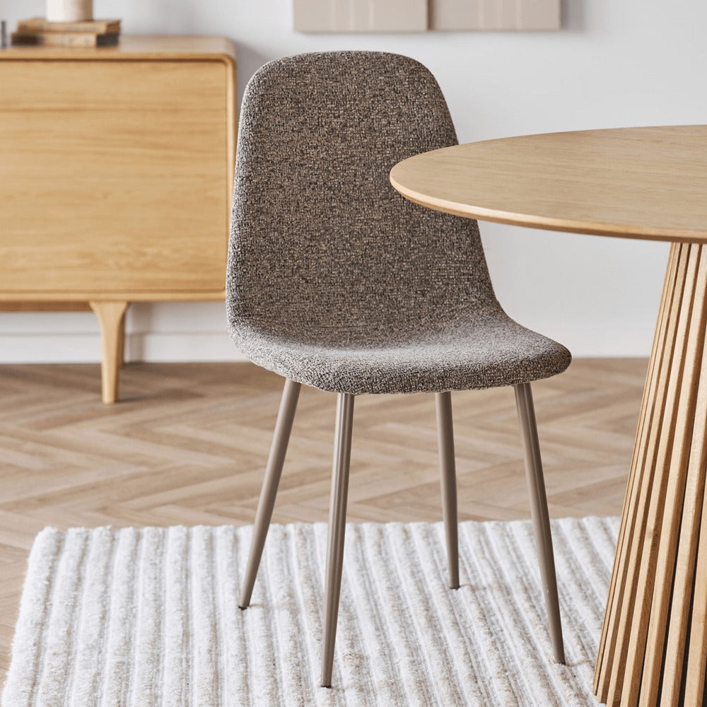 House Nordic Stockholm eetkamerstoel in bruine polyester stof met metalen poten, geplaatst aan een houten eettafel in Scandinavisch interieur.