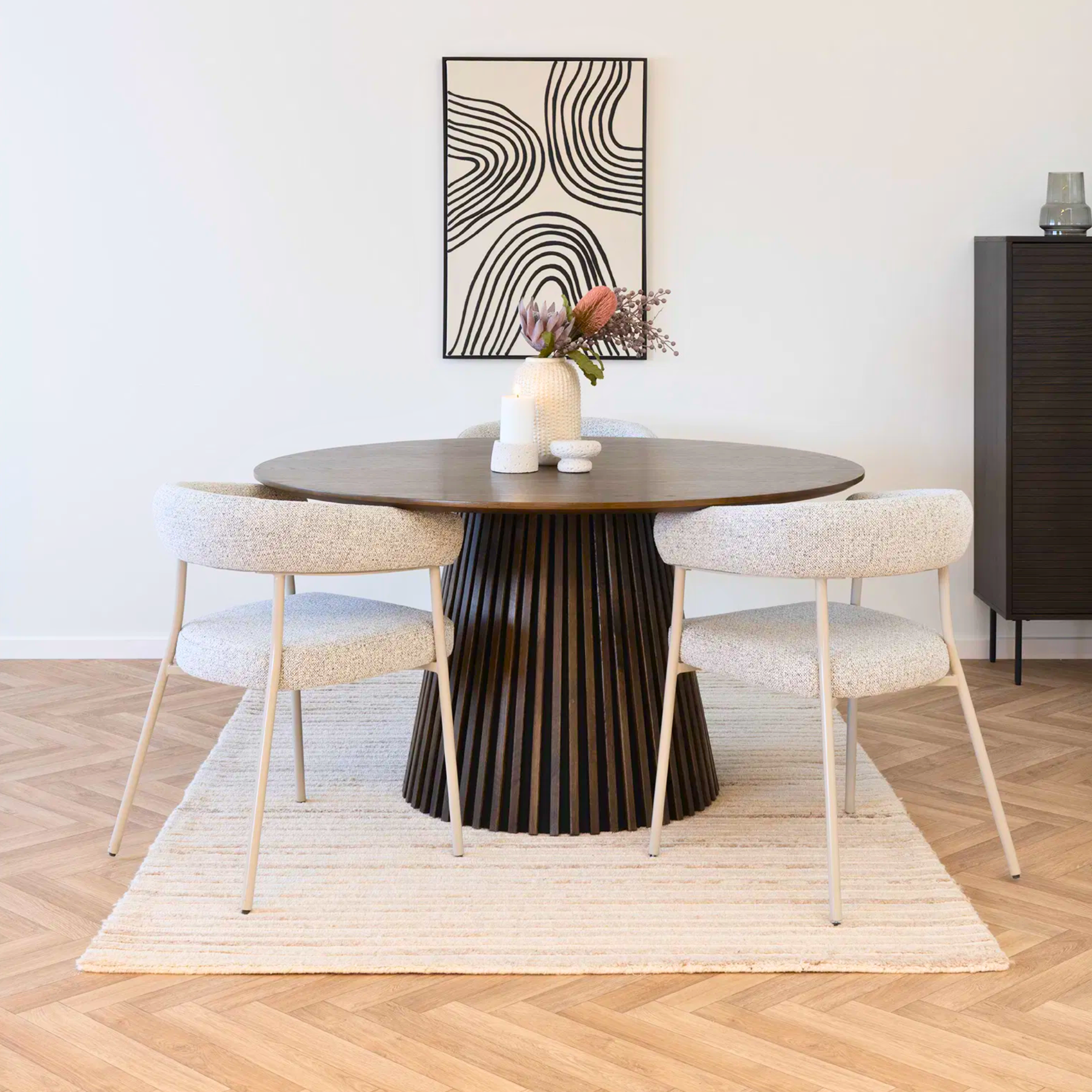 Twee Trivio bouclé eetkamerstoelen aan een ronde donkere houten tafel in modern Scandinavisch interieur.