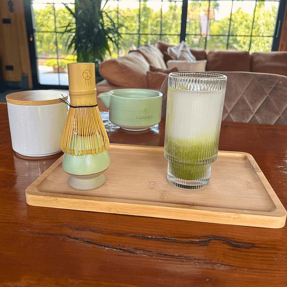 Matcha latte geserveerd met de Lunero matcha set, inclusief bamboo whisk, kom en houten tray.