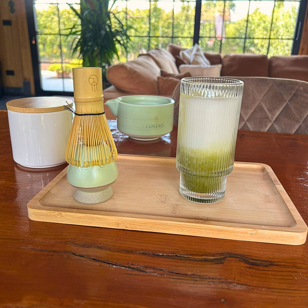Matcha latte geserveerd met de Lunero matcha set, inclusief bamboo whisk, kom en houten tray.