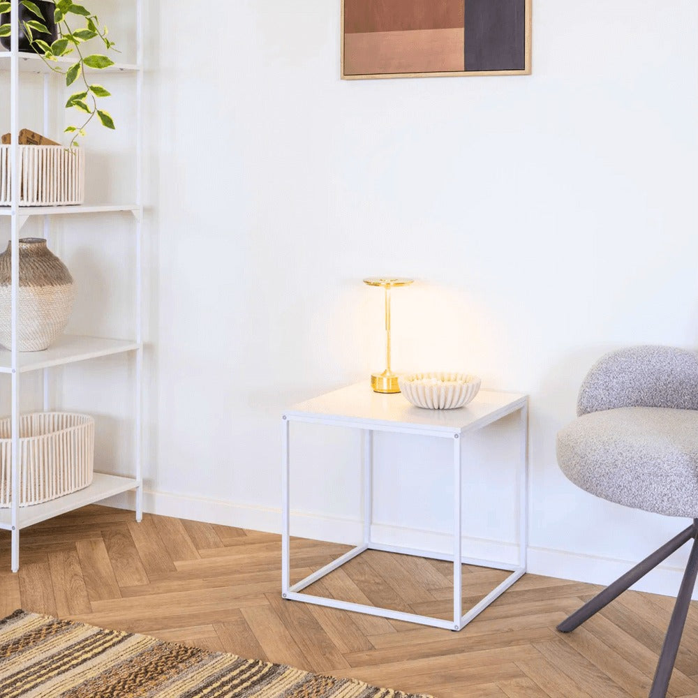 Gouden Lyneham LED tafellamp van House Nordic op een wit bijzettafeltje in een modern Scandinavisch interieur.