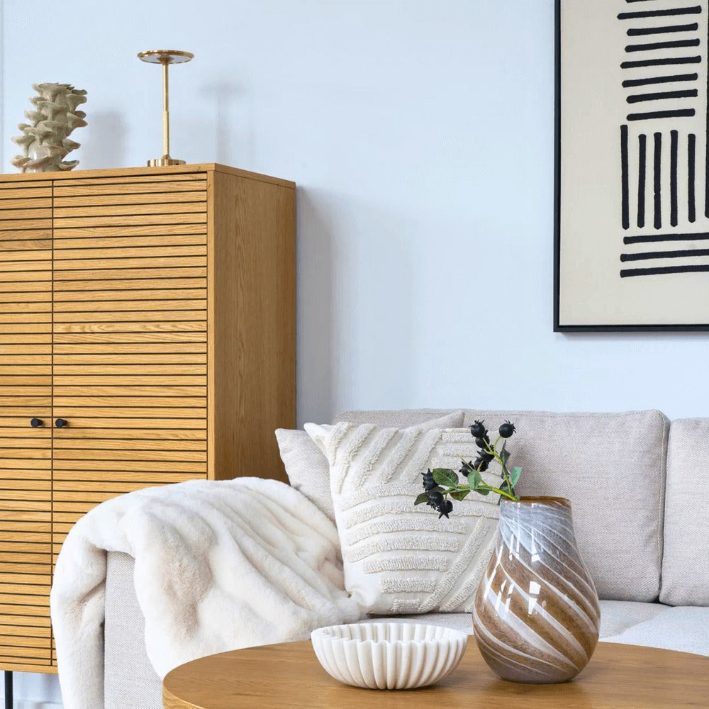 Gouden Lyneham LED tafellamp van House Nordic op een houten kast in een Scandinavisch woonkamerinterieur met neutrale tinten.