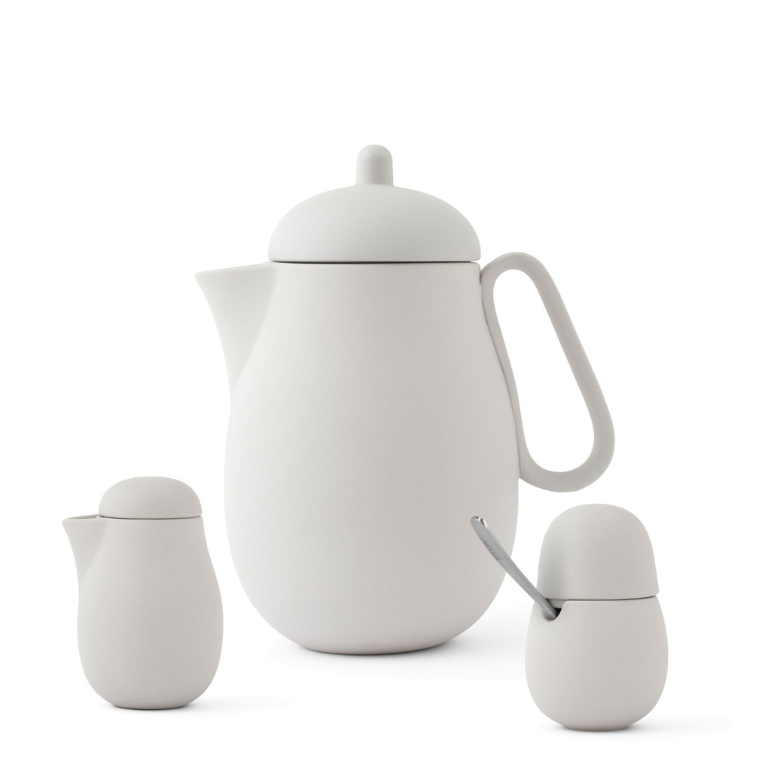 Minimalistische witte theeset van keramiek met theepot, melkkan en suikerpot met lepel.