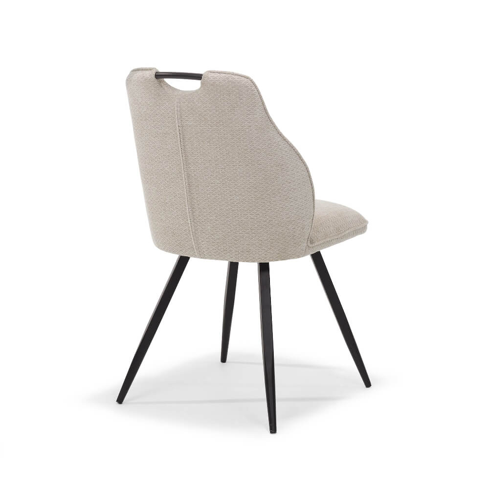 Achteraanzicht van de RV Design Adele eetkamerstoel in beige Retro Bliss stof met zwart metalen poten en geïntegreerd handvat, gefotografeerd op een witte achtergrond.