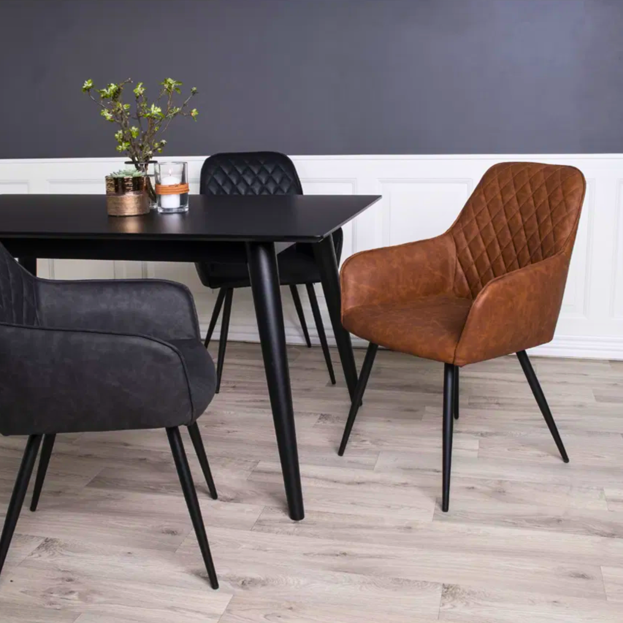 Harbo eetkamerstoel in vintage bruin PU-leer met zwarte metalen poten, gecombineerd met zwarte stoelen aan een moderne eettafel – House Nordic.