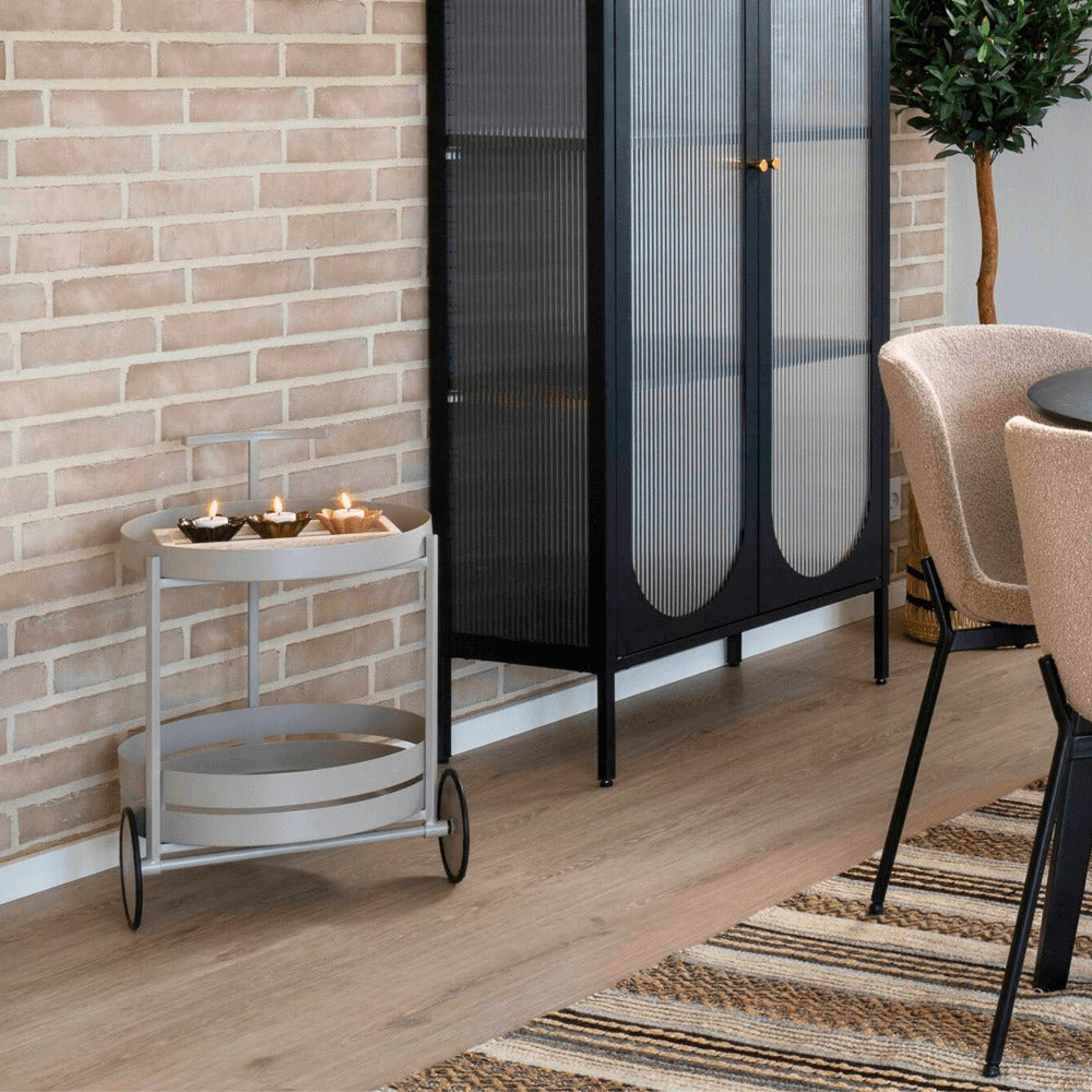 House Nordic Beja serveerwagen in grijs metaal – stijlvolle drankentrolley met ronde plateaus in een modern Scandinavisch interieur met houten vloer en zwarte kast.