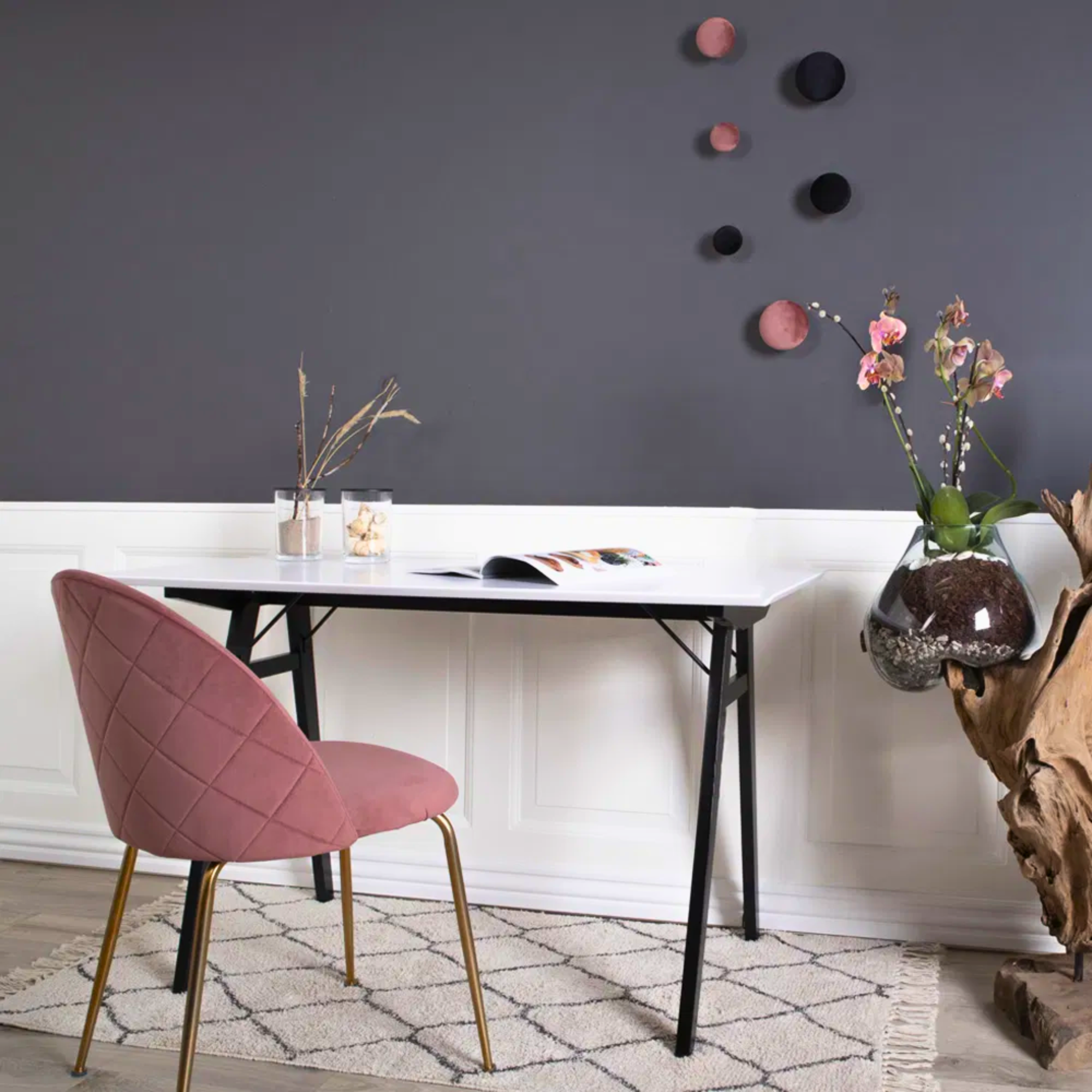 Roze velvet House Nordic Geneve eetkamerstoel met gouden poten bij een modern bureau met grijze muur en Scandinavische decoratie.