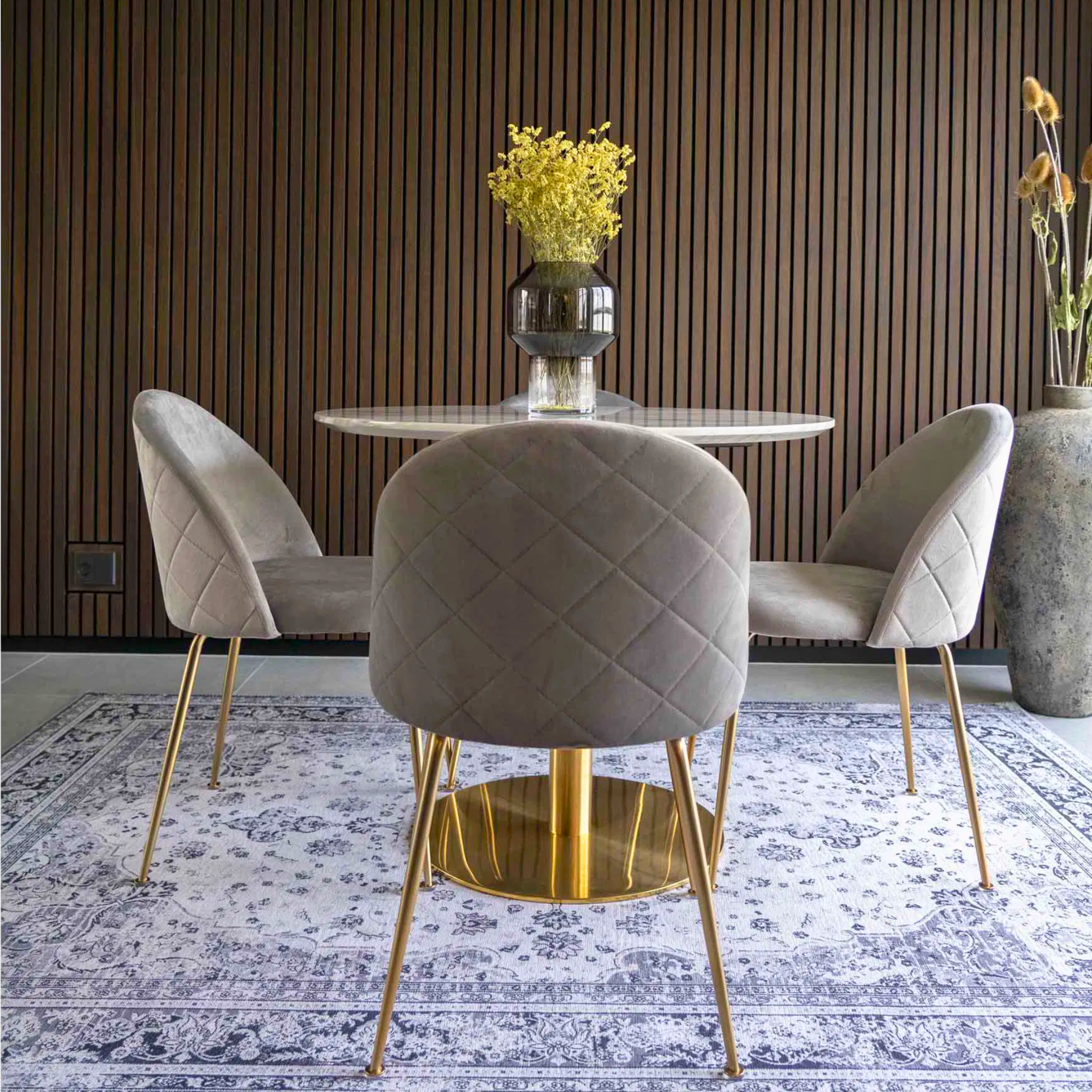 Set van grijs velvet House Nordic Geneve eetkamerstoelen met gouden poten rond een marmeren eettafel in modern Scandinavisch interieur.