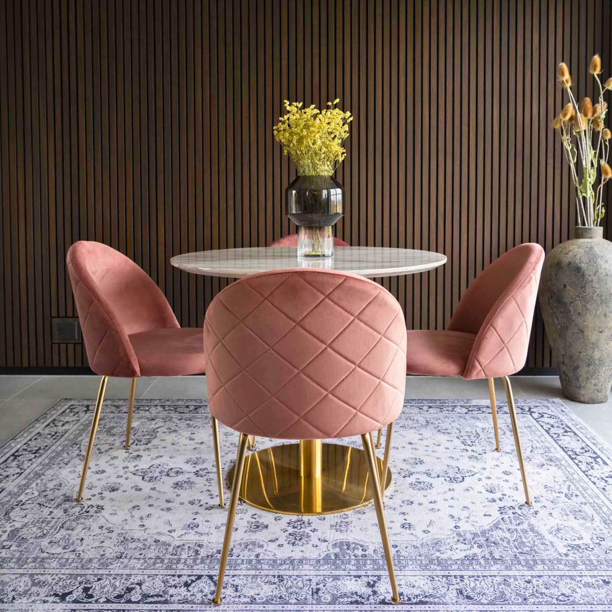 Set van roze velvet House Nordic Geneve eetkamerstoelen met gouden poten rond een marmeren eettafel in modern Scandinavisch interieur.