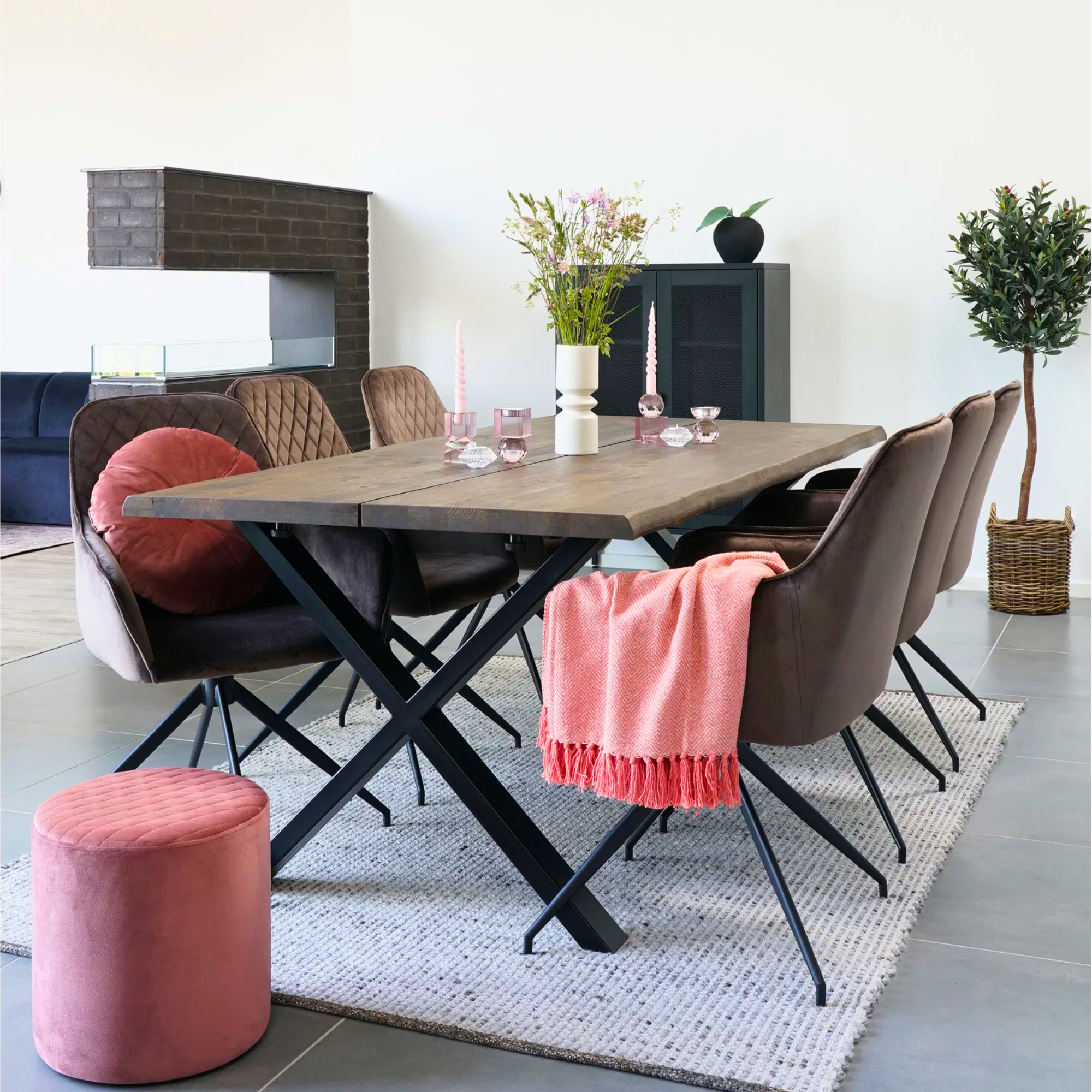 Scandinavische eetkamer met House Nordic Harbo eetkamerstoelen in lichtbruin velvet rond een houten tafel, gestyled met roze accenten en planten.
