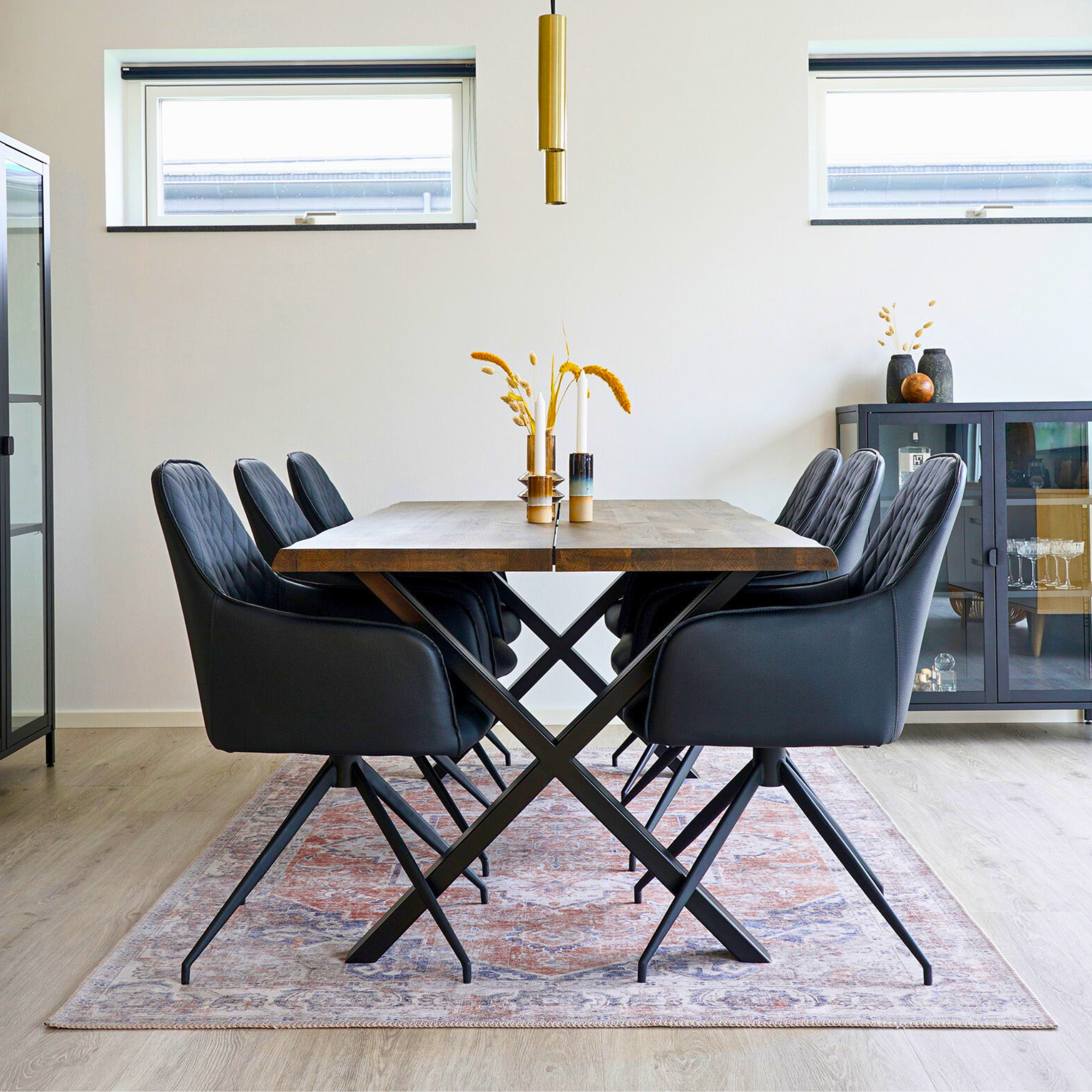 Zwarte House Nordic Harbo eetkamerstoelen rond een houten eettafel in een modern Scandinavisch interieur met lichte muren en gouden accenten.