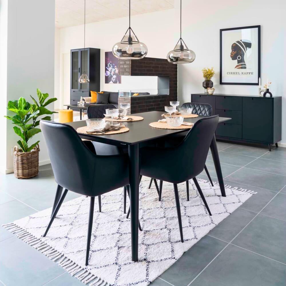 Set van zwarte House Nordic Harbo eetkamerstoelen rond eettafel in modern Scandinavisch interieur met zwarte accenten en natuurlijke decoratie.