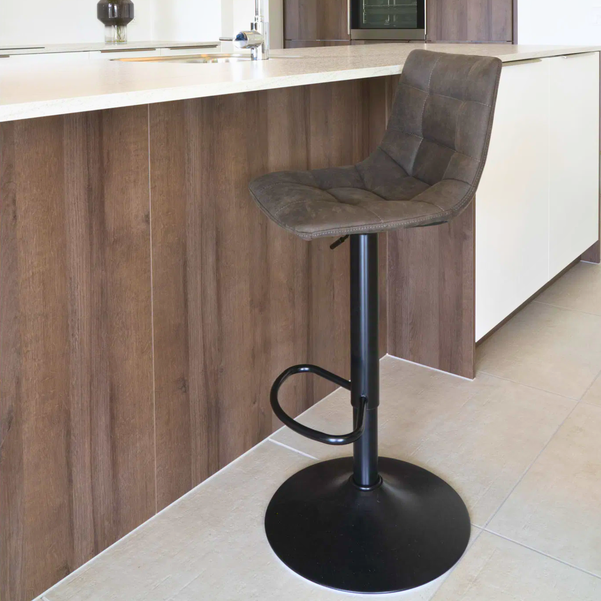 House Nordic Middelfart barkruk in donkergrijs microvezel met zwarte metalen poot, geplaatst aan een moderne houten keukentoonbank.