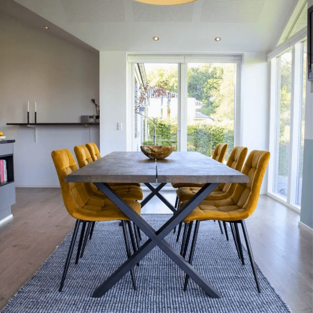 Moderne eetkamer met House Nordic Middelfart eetkamerstoelen in geel velvet met zwarte poten rond houten eettafel in lichte ruimte.