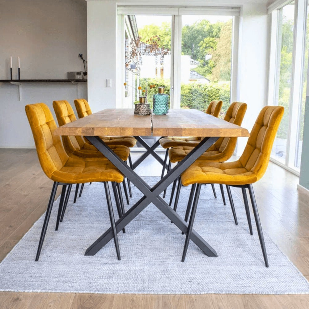 Scandinavisch interieur met House Nordic Middelfart eetkamerstoelen in geel velvet met zwarte poten rond houten eettafel in lichte eetkamer.